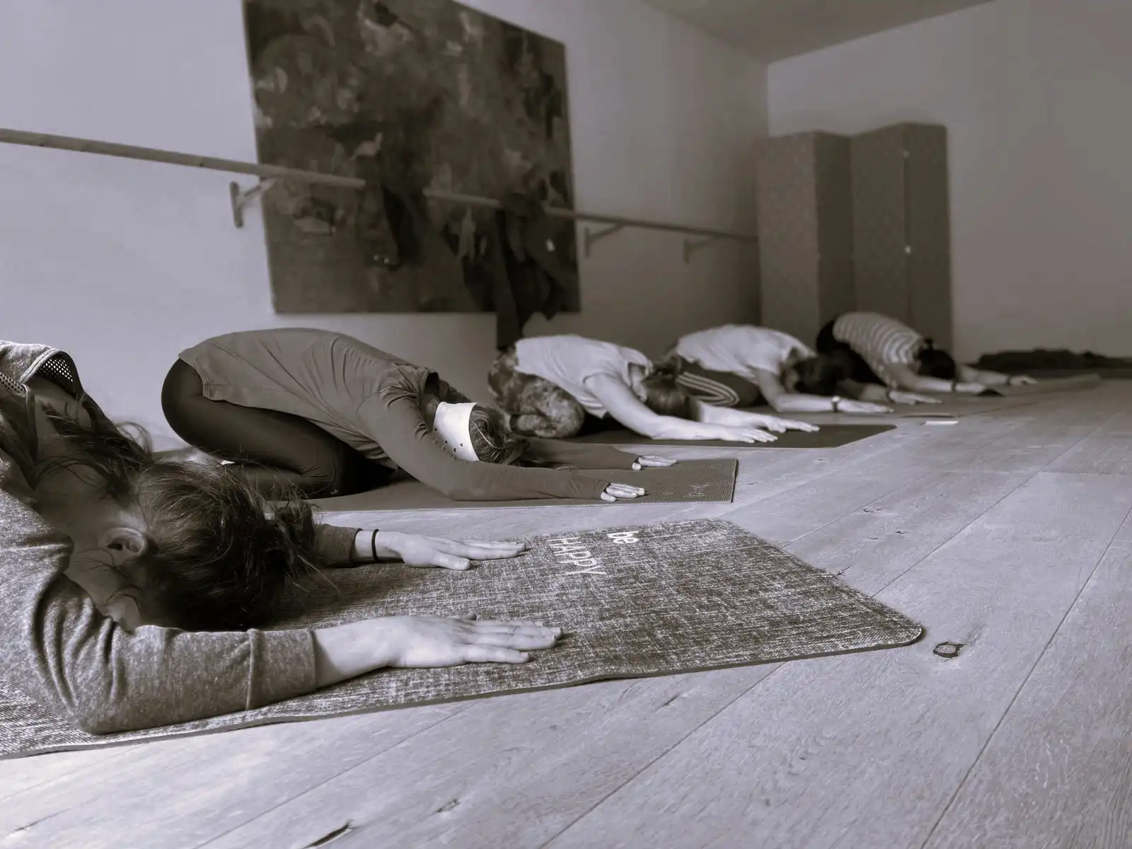 Mehrere Personen praktizieren Yoga in einem ruhigen Studio und befinden sich in der Kindhaltung auf Yogamatten.