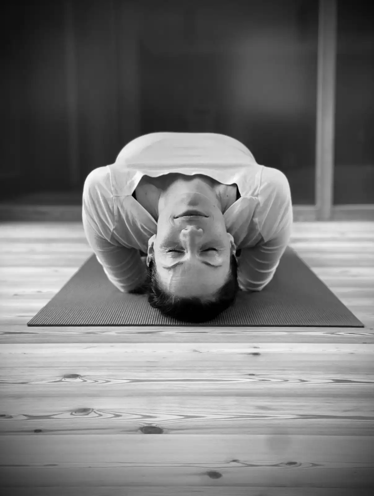 Person liegt entspannt in einer Yoga-Rückbeuge auf einer Matte, die Augen geschlossen.