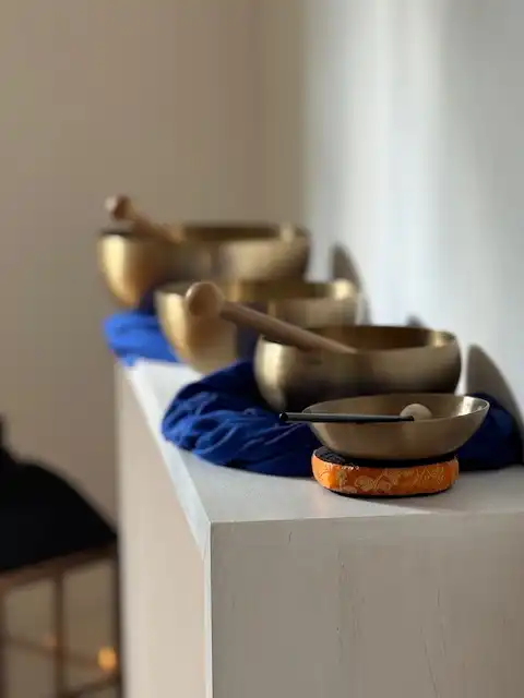 Mehrere tibetische Klangschalen mit Holzklöppeln auf blauen Tüchern für Yoga und Meditation bei einem Yoga-Retreat.