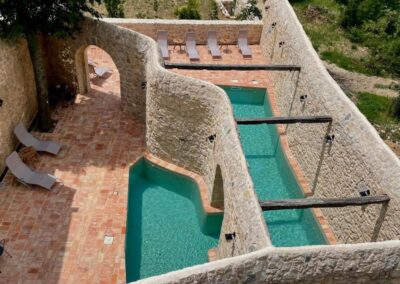 Naturstein-Poolanlage mit türkisfarbenem Wasser und Sonnenliegen auf einer mediterranen Terrasse im Hotel Balatura in Kroatien – Ort für Entspannung während eines Retreats.