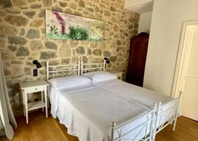 Gemütliches, liebevoll renoviertes Schlafzimmer mit Natursteinwand, Doppelbett und hellen Möbeln im Hotel Balatura in Kroatien – ruhige Unterkunft für Yogaretreat Gäste.